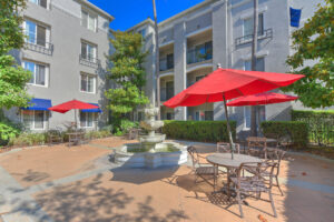 Exterior Outdoor Courtyard, bistro tables, Red Umbrellas, 3-tiered fountain, building exteriors, 4 stories.